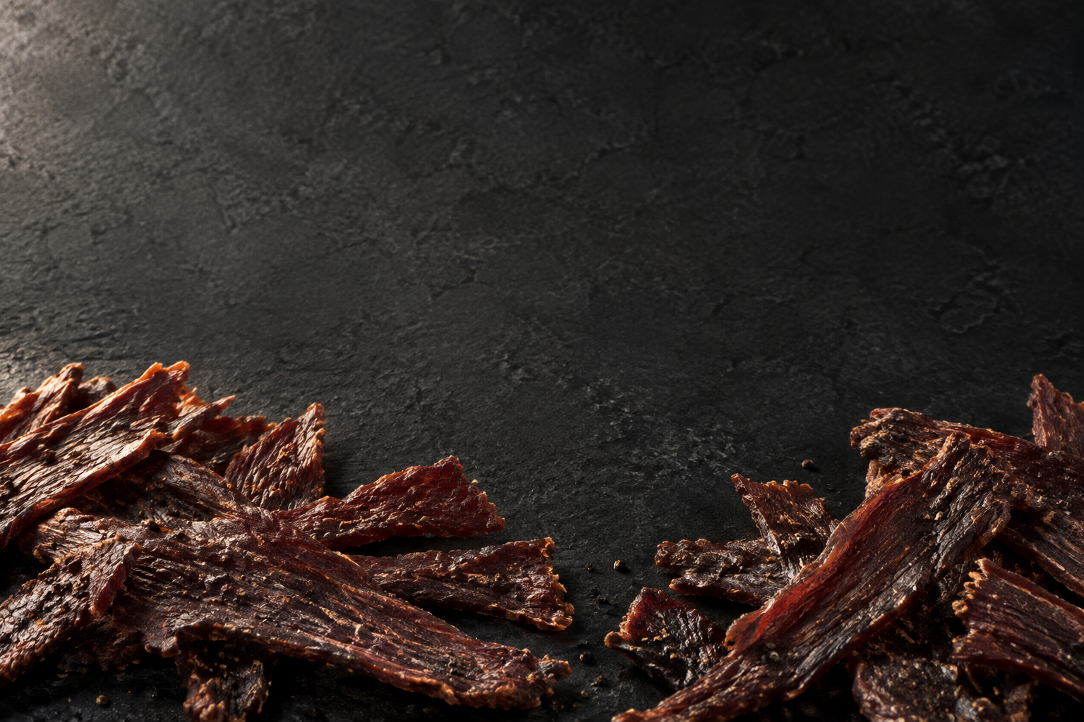 Illustrative loose beef jerky on a dark stone surface
